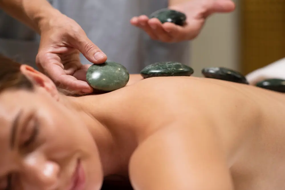 What You Need to Know About Hot Stone Therapy in Washington PA Therapist placing heated stones during hot stone therapy Washington PA
