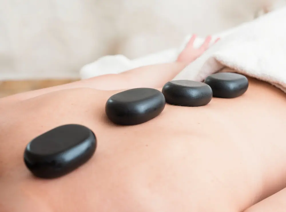 Muscle tightness and stiffness Therapist placing hot stones during massage therapy Washington PA